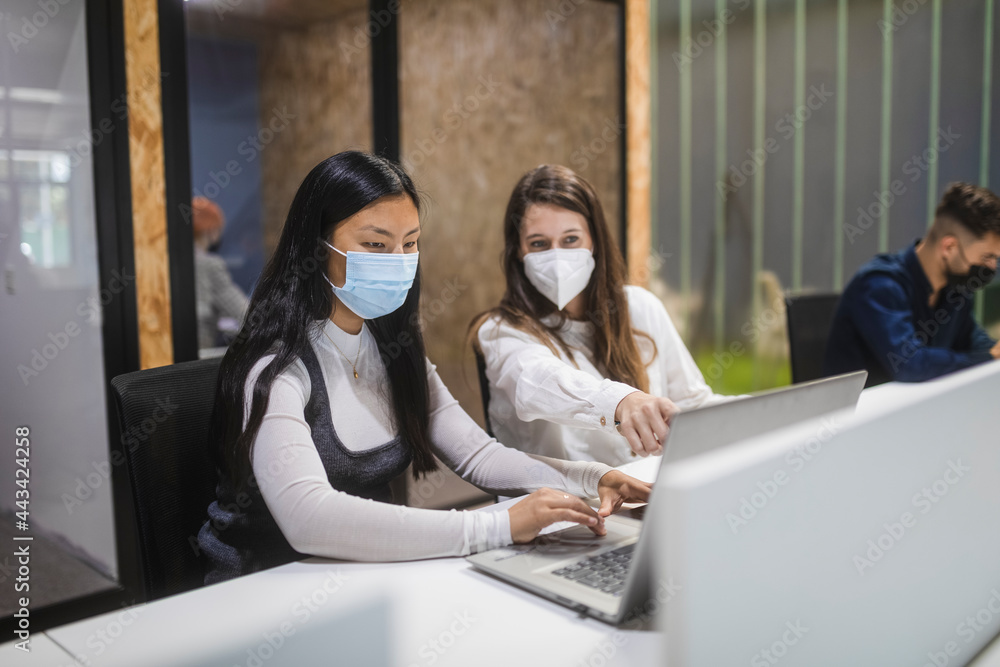 Multiethnic women in masks working together in office Multiethnic women in masks working together in office
