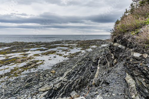 View on a cloudy day on the St Lawrence river, the shore and the cliffs of Gaspesie from the Petite Vallée Marina, near the scenic route 132 (Quebec, Canada) photo