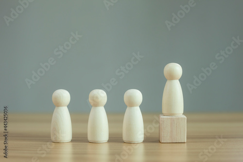 Wooden person model among people on black background, Leadership concept.