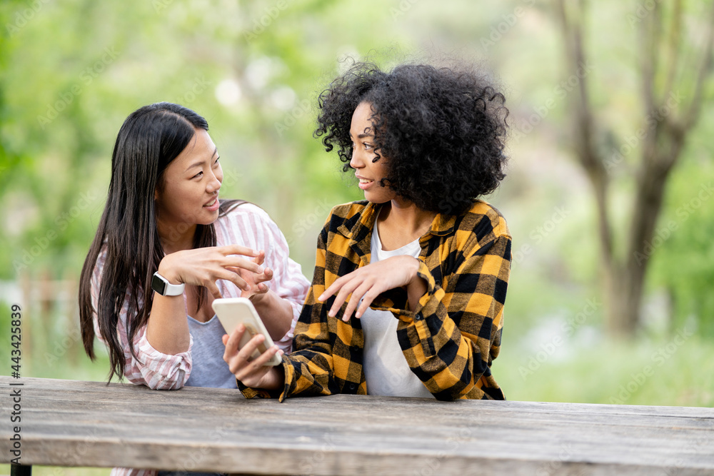 Multiethnic couple of lesbian women gossiping together Multiethnic couple of lesbian women gossiping together