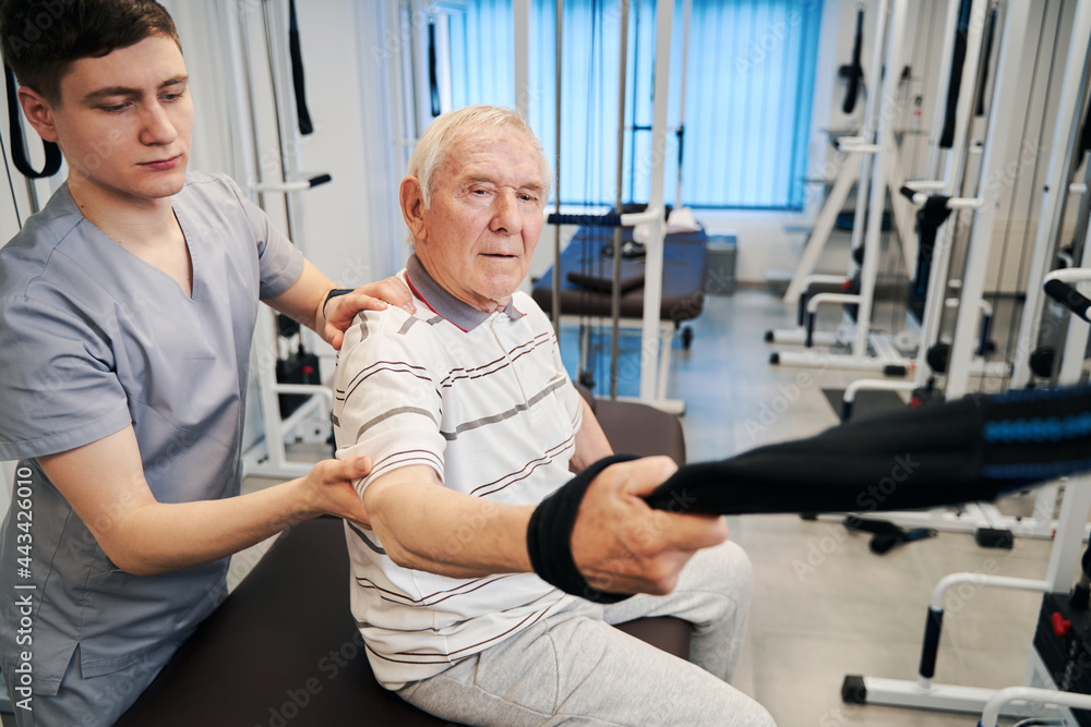 Confident senior citizen doing arm exercise on rehabilitation equipment Confident senior citizen doing arm exercise on rehabilitation equipment