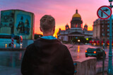 A young man walks during a pink sunset in the center of St. Petersburg with a view of St. Isaac's Cathedral