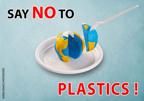 WorldEarth Day concept. Plastic free concept. Say NO to plastics. Pollution problem concept. A plastic plug stuck into the planet Earth. Plasticine earth model on a plastic plate photo