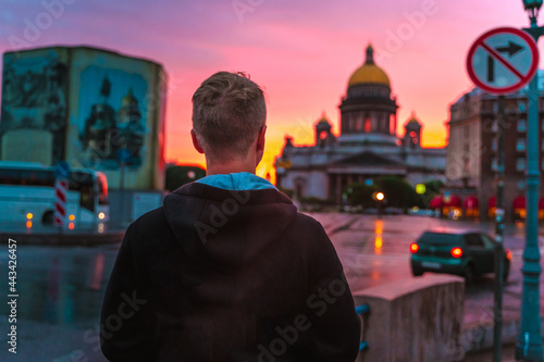 A young man walks during a pink sunset in the center of St. Petersburg with a view of St. Isaac s Cathedral