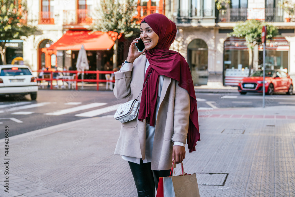 Smiling Muslim woman with shopping bags in city Smiling Muslim woman with shopping bags in city