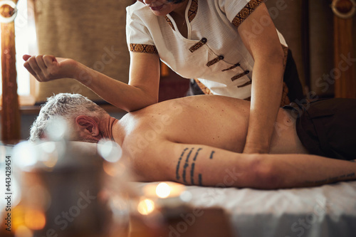 Grizzled male during traditional thai massage for back