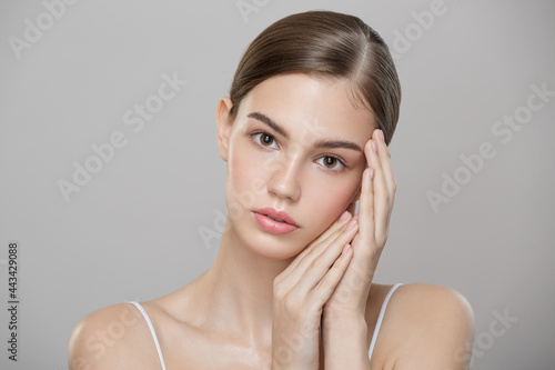 Beauty portrait of a young beautiful girl with clean skin. Gray background.