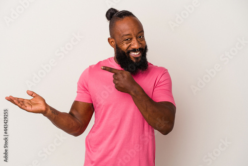 African american man with beard isolated on pink background excited holding a copy space on palm.