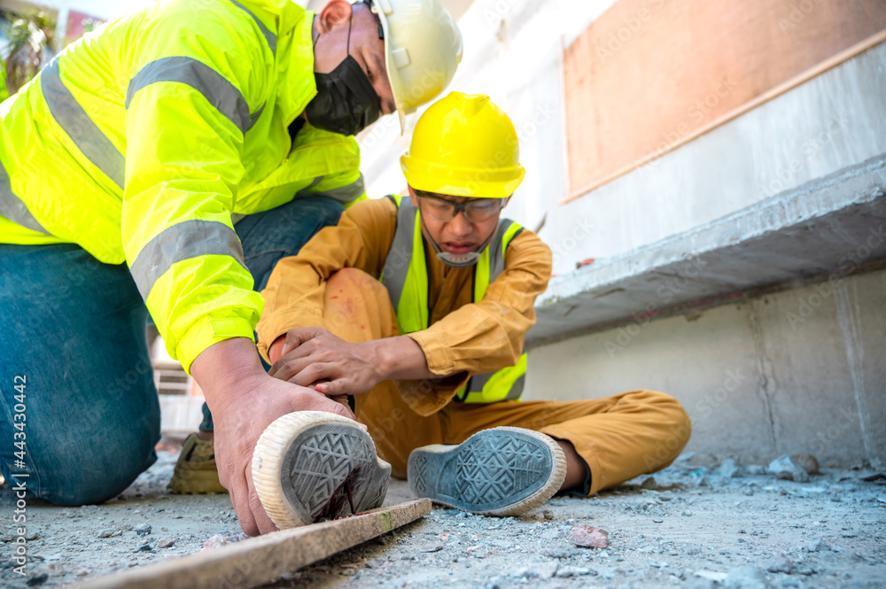 Construction worker has accident stepping on nail at construction site. Emergency help engineer provide first aid to construction workers in accident. Safety team help construction worker has accident Construction worker has accident stepping on nail at construction site. Emergency help engineer provide first aid to construction workers in accident. Safety team help construction worker has accident