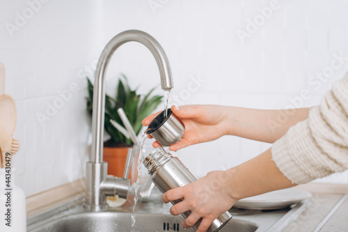 Woman washes a metal reusable bottle with an eco-brush.  Zero waste 