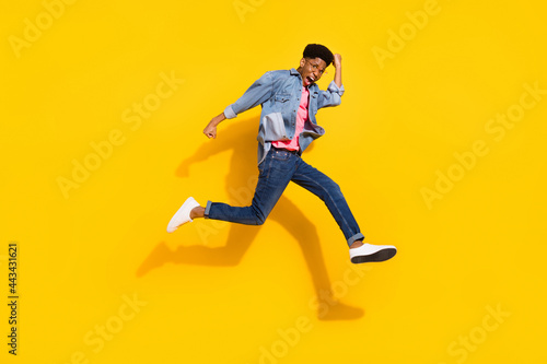 Full body photo of crazy afro american young man jump up run empty space winner isolated on yellow color background