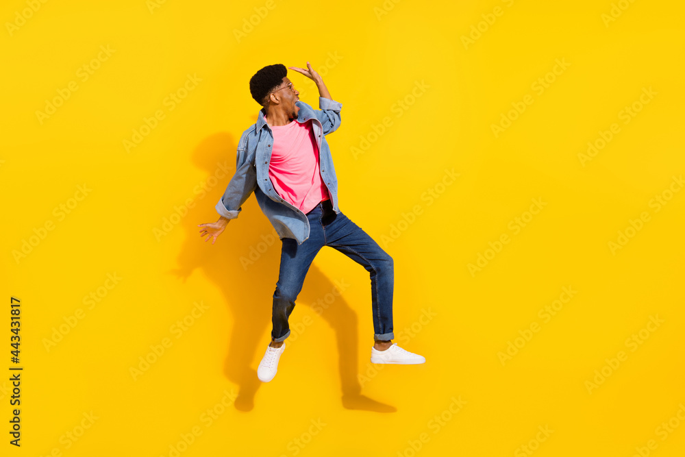 Full size photo of young afro american man look empty space scream jump isolated on yellow color background