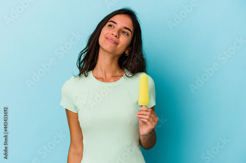 Young caucasian woman holding an ice cream isolated on blue background dreaming of achieving goals and purposes