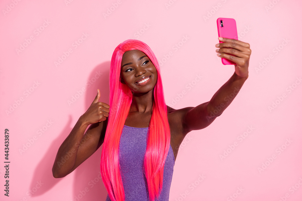 Photo portrait of african american woman taking selfie showing thumb up isolated on pastel pink colored background Photo portrait of african american woman taking selfie showing thumb up isolated on pastel pink colored background
