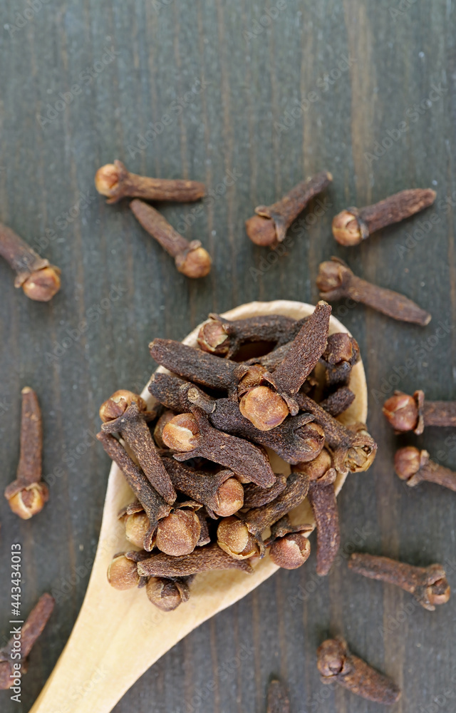 Top View of Dried Cloves on Wooden Spoon with Some Scattered on the Background Top View of Dried Cloves on Wooden Spoon with Some Scattered on the Background
