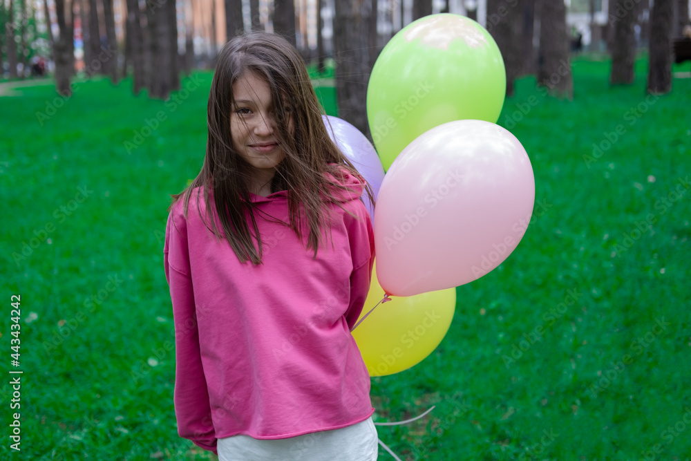Naklejka premium sweet tween brunette girl in pink holding colorful balloons outdoors. party, birthday concept. summertime. happy kids