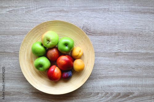 Bowl of various colorful fruit on a wooden table. Top view.
