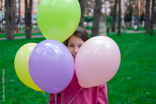 Photography pretty tween teenager brunette girl in pink holding colorful hot air balloons outdoors