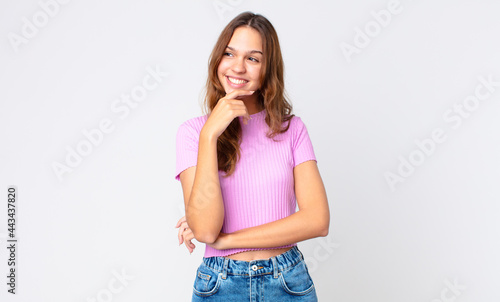 young pretty woman smiling with a happy, confident expression with hand on chin photo