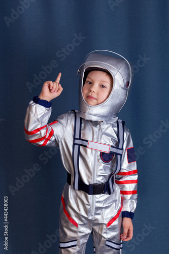 Cosmonaut concept. Portrait of little boy in cosmonaut costume and helmet with a raised forefinger up. Isolated background with copy space.