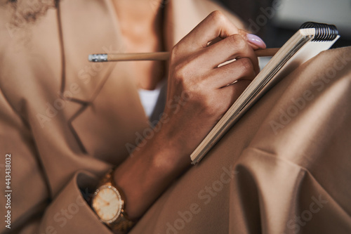 Hand of woman with watch on wrist holding pencil