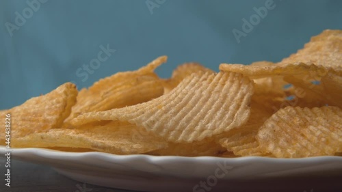 Chips falling on isolated background. Stock footage. Delicious chips fall and cause appetite. Harmful snacks in form of potato chips. Favorite junk food