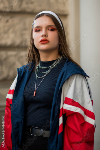 Beautiful country girl in 90s style. Back in time 90s 80s. Stylish girl in retro colourful vintage coat. dressed in street style clothes with chains around neck for a walk. Youth and lifestyle concept photo