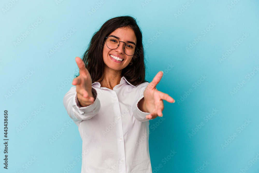 Young caucasian woman isolated on blue background feels confident giving a hug to the camera. Young caucasian woman isolated on blue background feels confident giving a hug to the camera.