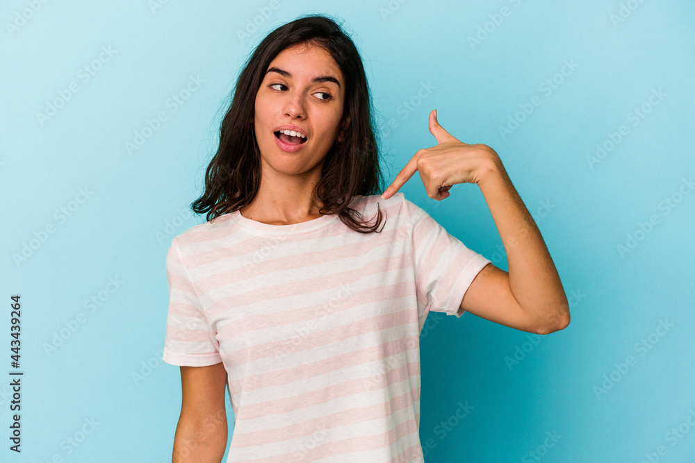 Young caucasian woman isolated on blue background person pointing by hand to a shirt copy space, proud and confident Young caucasian woman isolated on blue background person pointing by hand to a shirt copy space, proud and confident