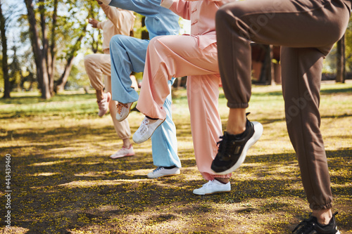 Raised legs of four people, doing exercise in park photo
