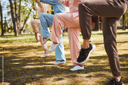 Tableau sur toile Raised legs of four people, doing exercise in park