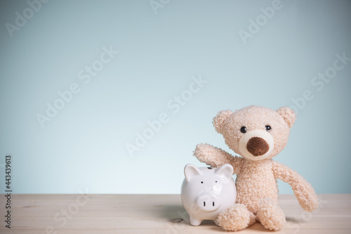 Savings money to buy a home for the future. Little brown teddy bears with piggy banks on an old wooden table with copy space. Concept loan, banking, and save money.