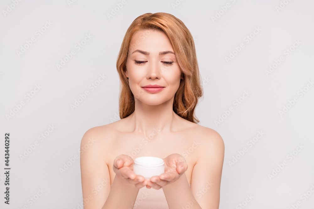Portrait of attractive woman holding on palms new novelty bio cream isolated over grey pastel color background Portrait of attractive woman holding on palms new novelty bio cream isolated over grey pastel color background