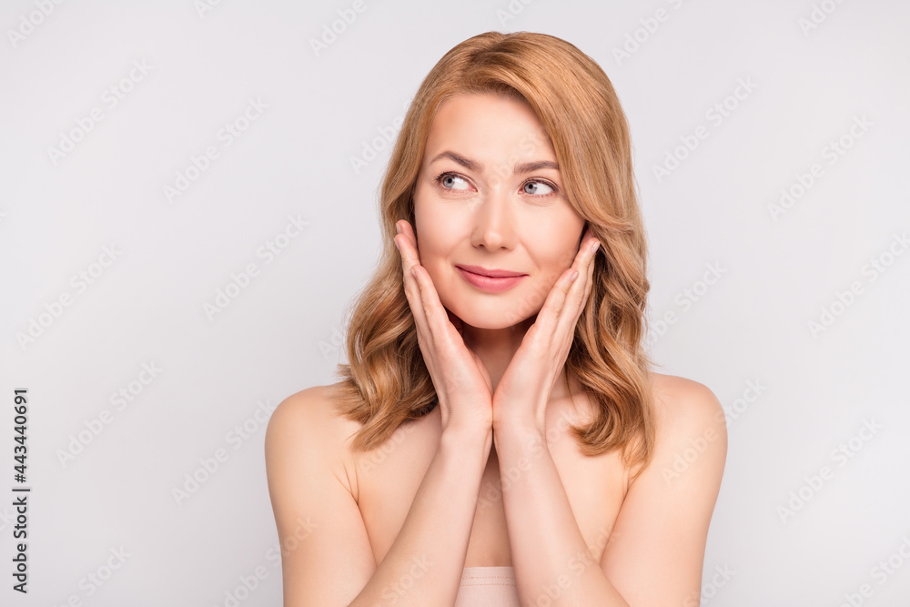 Portrait of attractive healthy woman washing face looking aside copy space ad isolated over grey pastel color background Portrait of attractive healthy woman washing face looking aside copy space ad isolated over grey pastel color background