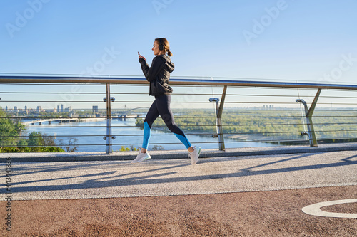 Jolly young female going jogging with smartphone