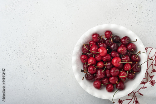 Cherry with water drops on white bowl on white stone table. Fresh ripe cherries. Sweet red cherries. Top view. Rustic style. Fruit Background