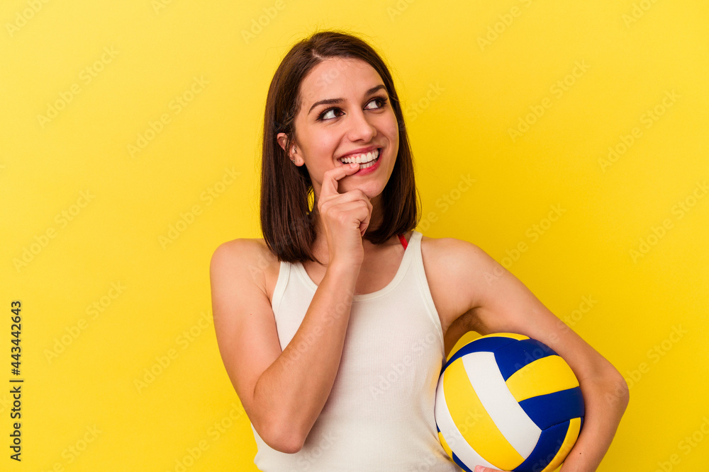 Young caucasian woman playing volleyball isolated on yellow background relaxed thinking about something looking at a copy space.