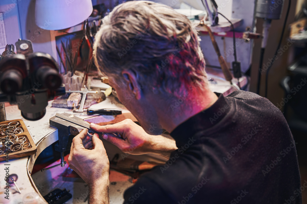Jewelry craftsman using hand file while working on product