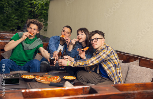 Group of friends, young men and woman drinking beer and watching sport match together outdoors. Concept of friendship, leisure activity, emotions.