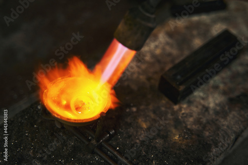 Flame from blowtorch melting metal for jewelry piece