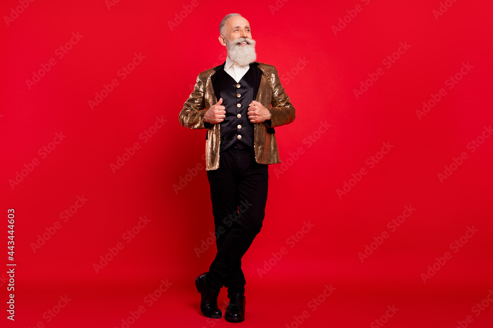 Fototapeta premium Full length photo of charming old man look empty space smile magician comedian isolated on red color background