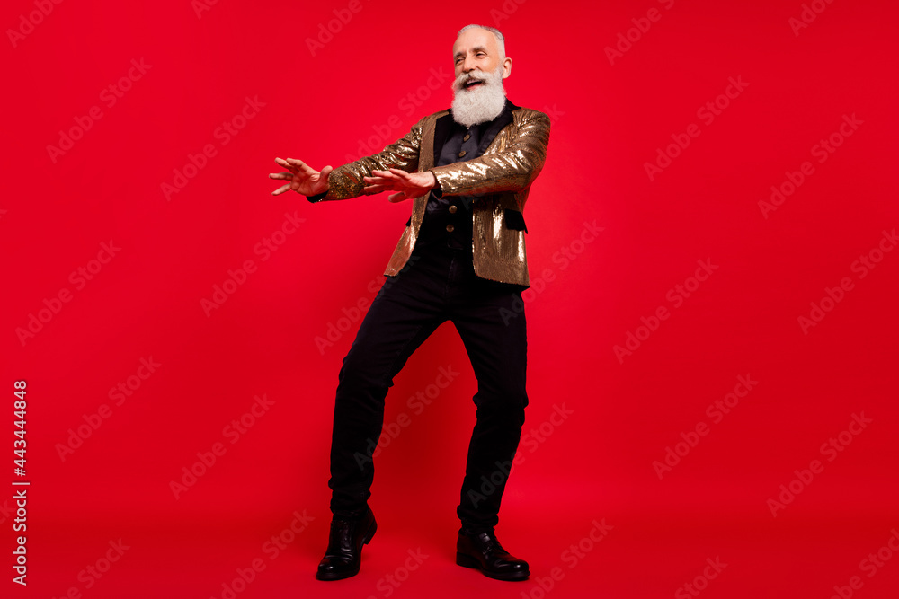 Full body photo of cheerful positive young man look empty space dance isolated on red color background Full body photo of cheerful positive young man look empty space dance isolated on red color background