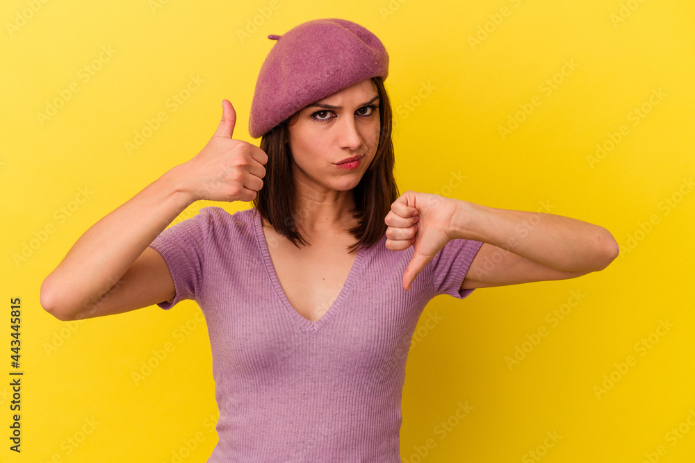 Young caucasian woman isolated on yellow background showing thumbs up and thumbs down, difficult choose concept Young caucasian woman isolated on yellow background showing thumbs up and thumbs down, difficult choose concept