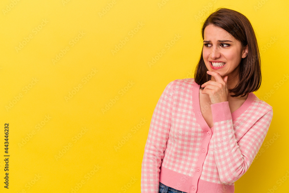 Young caucasian woman isolated on yellow background touching back of head, thinking and making a choice. Young caucasian woman isolated on yellow background touching back of head, thinking and making a choice.