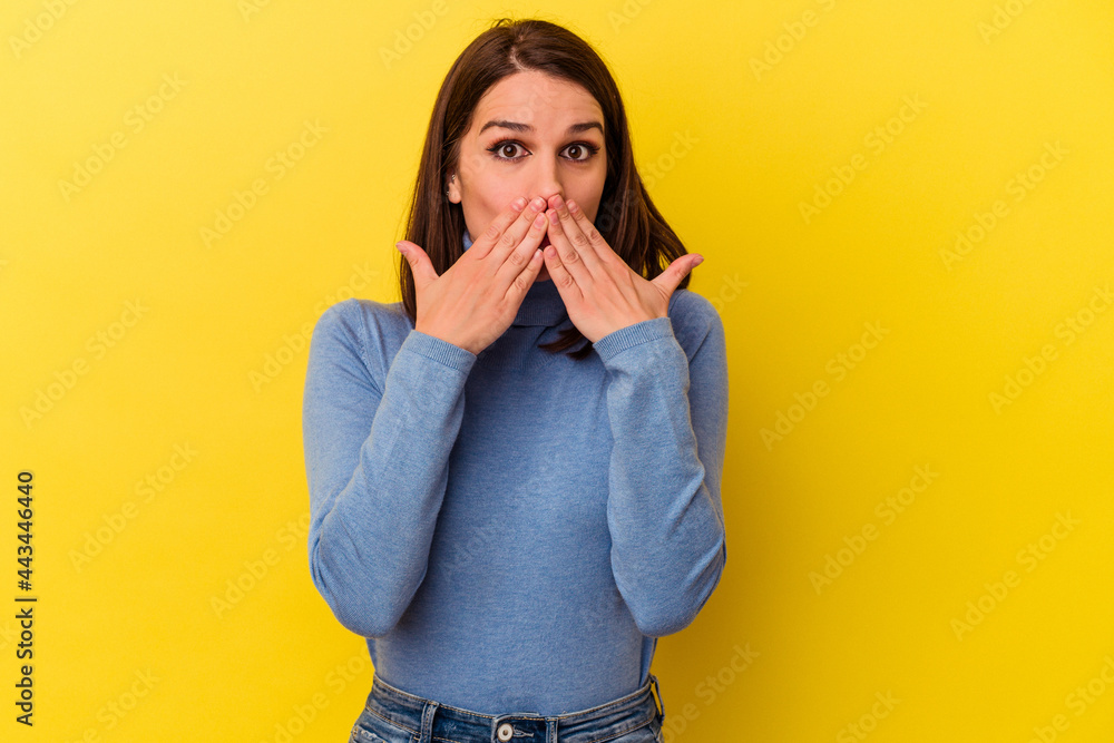Young caucasian woman isolated on yellow background shocked covering mouth with hands. Young caucasian woman isolated on yellow background shocked covering mouth with hands.
