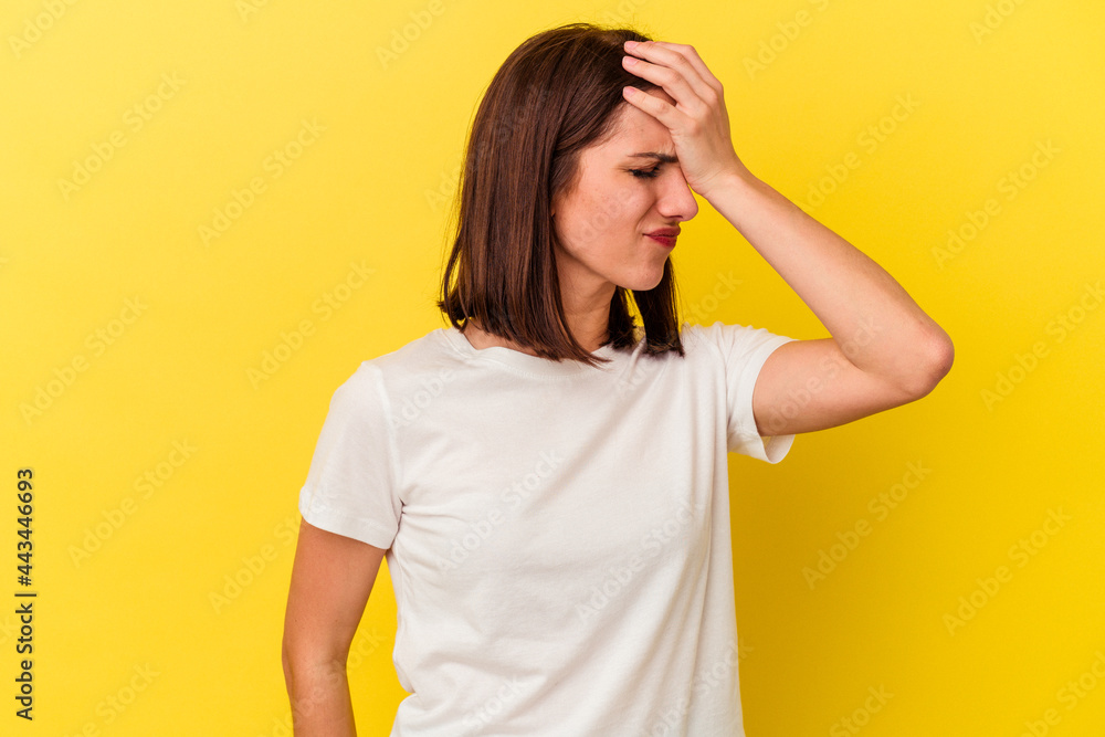 Young caucasian woman isolated on yellow background having a head ache, touching front of the face. Young caucasian woman isolated on yellow background having a head ache, touching front of the face.