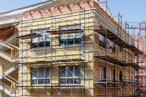 Thermal insulation of a red brick house with mineral wool. The use of scaffolding when building a house.