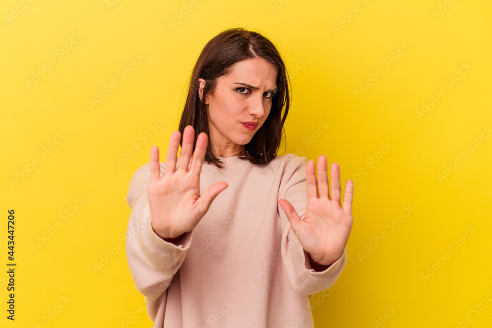 Young caucasian woman isolated on yellow background standing with outstretched hand showing stop sign, preventing you. Young caucasian woman isolated on yellow background standing with outstretched hand showing stop sign, preventing you.