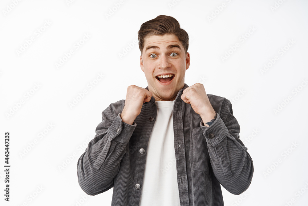 Close up of surprised and excited guy winning something, looking in awe with hands near chest, cheering, triumphing from win, achieve goal, receive great positive news Close up of surprised and excited guy winning something, looking in awe with hands near chest, cheering, triumphing from win, achieve goal, receive great positive news