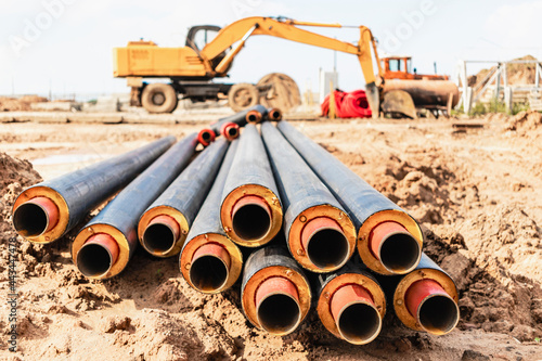 Hot water and heating pipes with an excavator in the background. Cold and hot water, heating and heating system of apartments in the house.